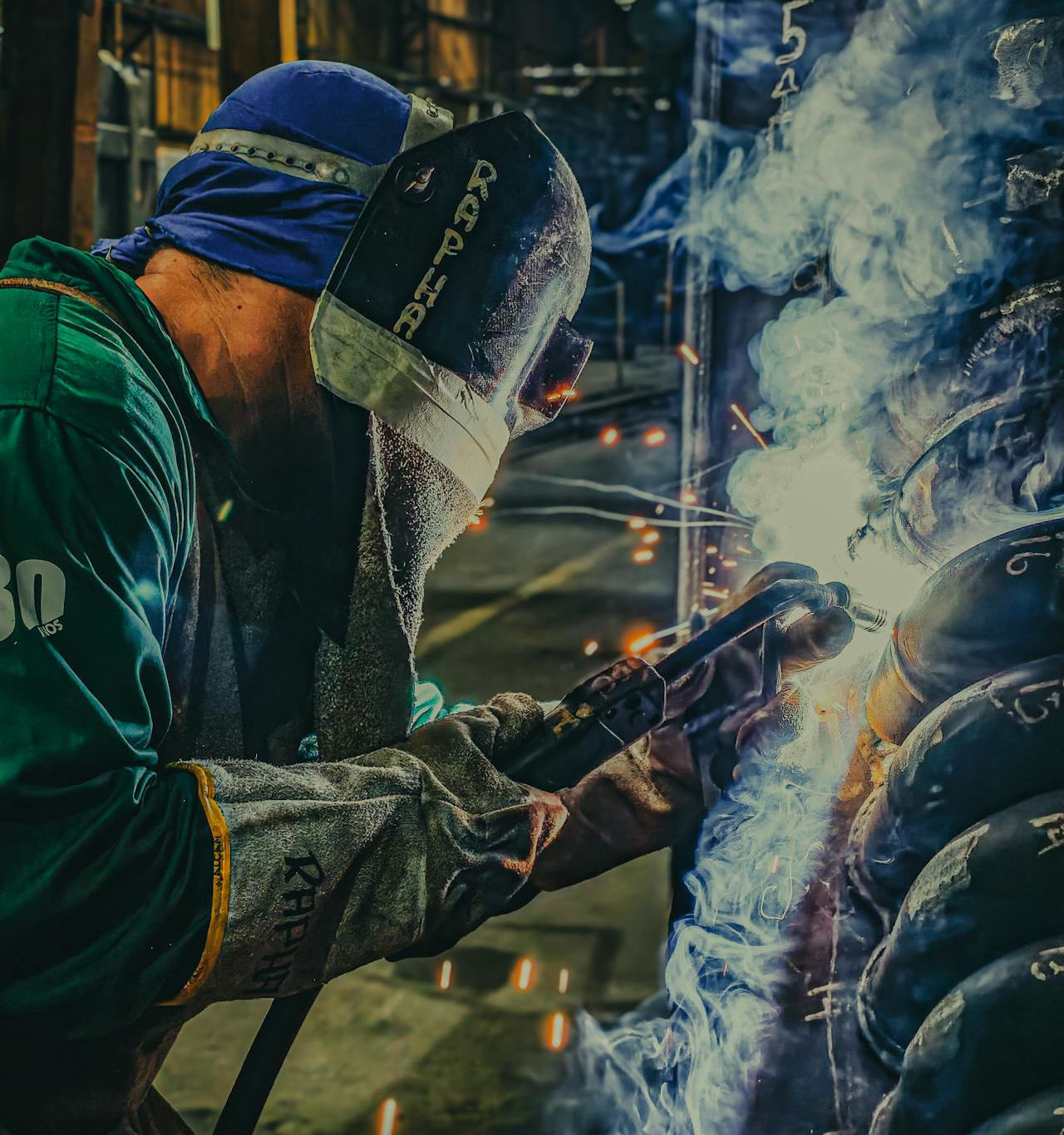 A worker wearing personal protective equipment (PPE) is using a construction power tool in a factory.
